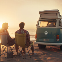 Dos chicos sentados en sillas viendo el anochecer en la playa disfrutando de la tranquilidad que da haber alquilado su furgoneta camper con MyAirvan.com